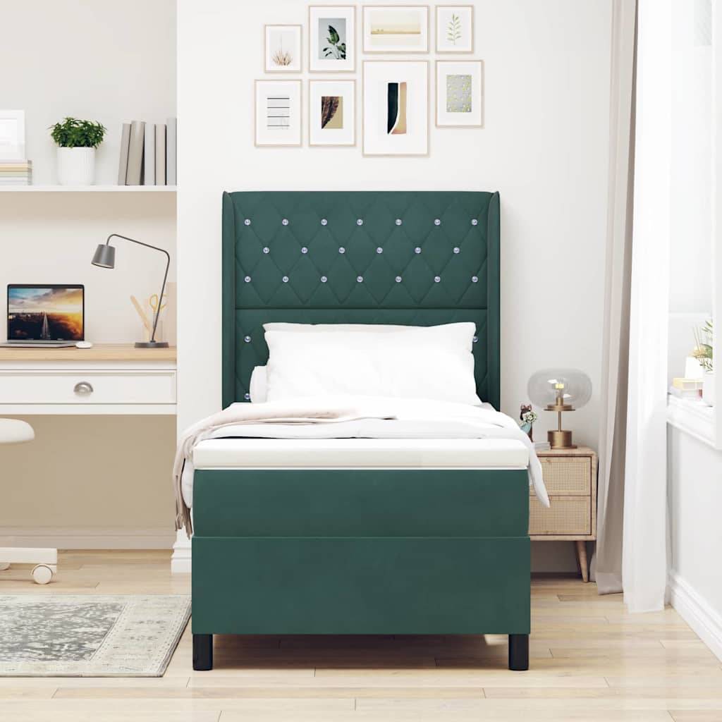 Ein ordentlich eingerichtetes Schlafzimmer mit einem Bett mit grünem gepolstertem Kopfteil, einem Nachttisch mit einer Lampe, einem an der Wand montierten Schreibtisch und gerahmten Bildern darüber.