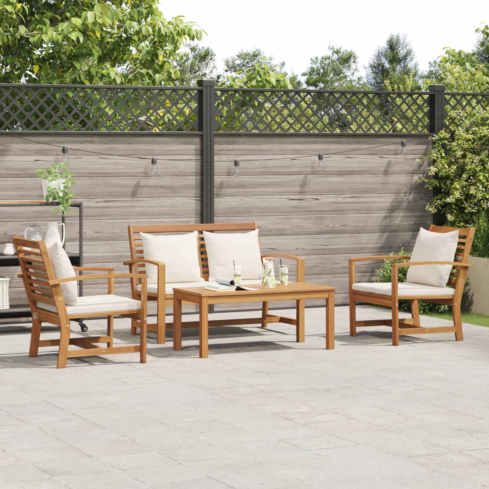 Ein Terrassenmöbelset mit einem Holztisch und Stühlen, gepolsterten Sitzmöbeln und einem Servierwagen mit Grünpflanzen in einem eingezäunten Außenbereich.