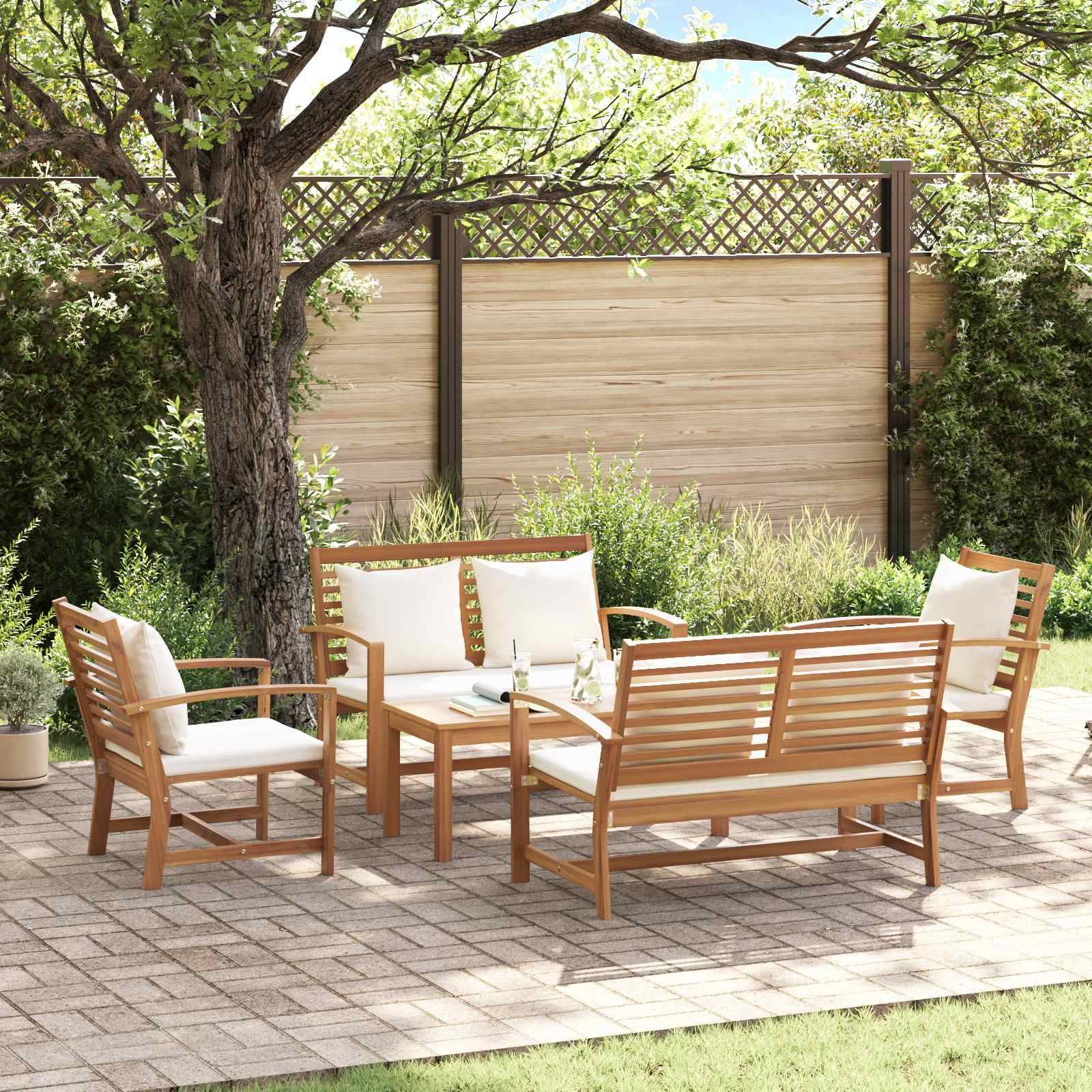 Outdoor-Terrassenset mit Holzstühlen, einer Sitzbank und einem Tisch auf einer Steinpflasterung, umgeben von Grünpflanzen und einem Holzzaun.