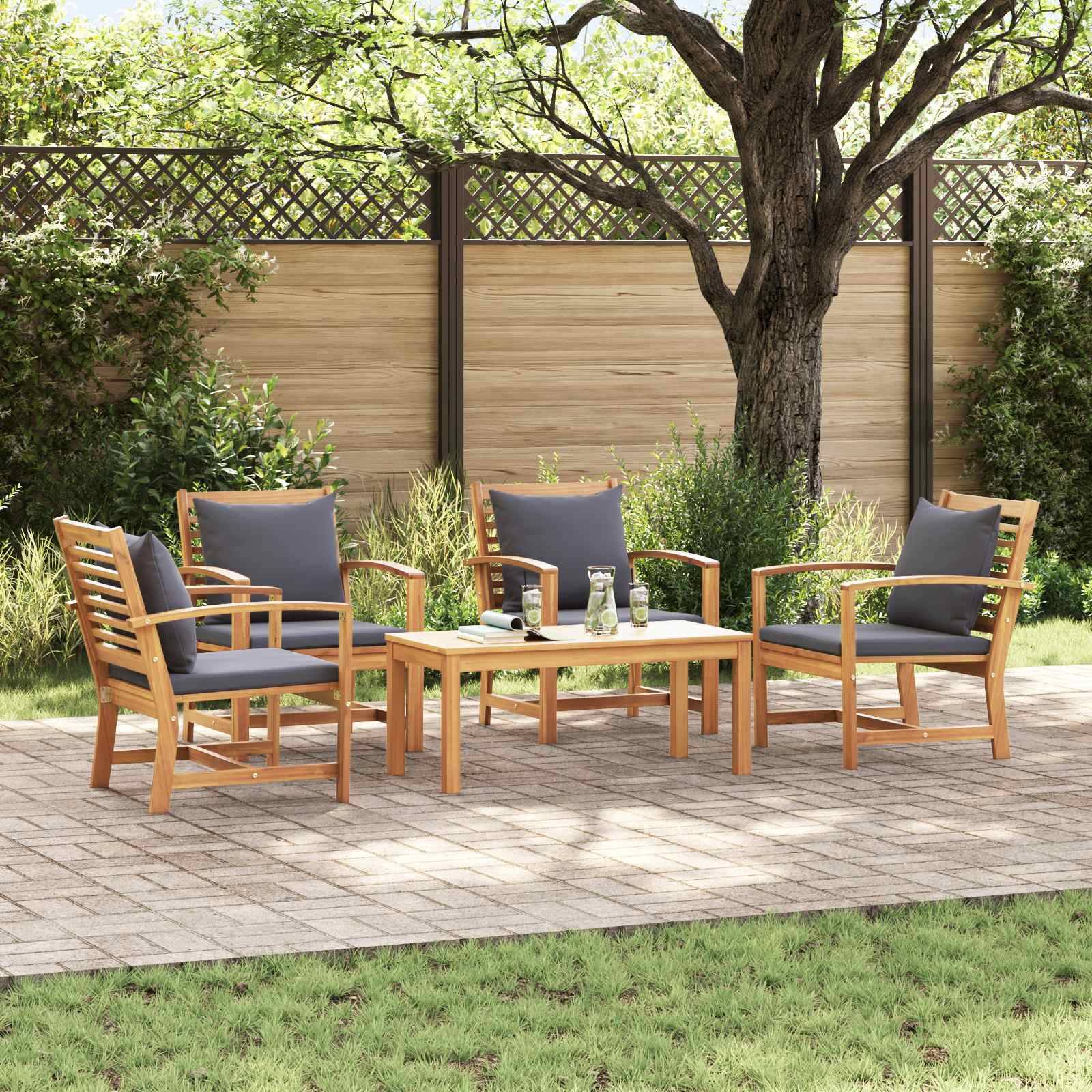 Ein Holz-Gartenmöbel-Set mit vier Sesseln und einem Tisch steht auf einer Terrasse, umgeben von Gras und Bäumen, mit einem Holzzaun im Hintergrund.