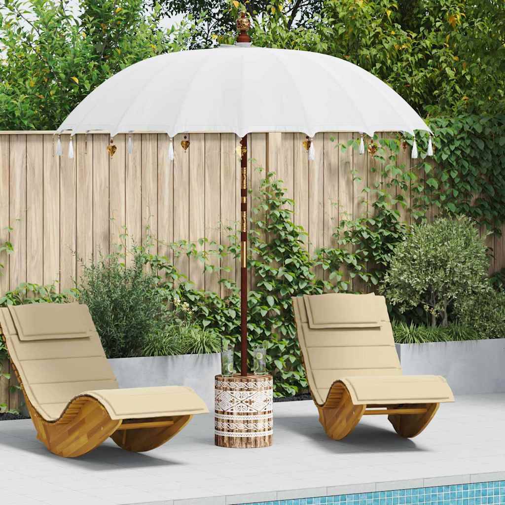Zwei beige Loungesessel unter einem weißen Sonnenschirm am Pool, umgeben von üppiger Vegetation und einem Holzzaun.