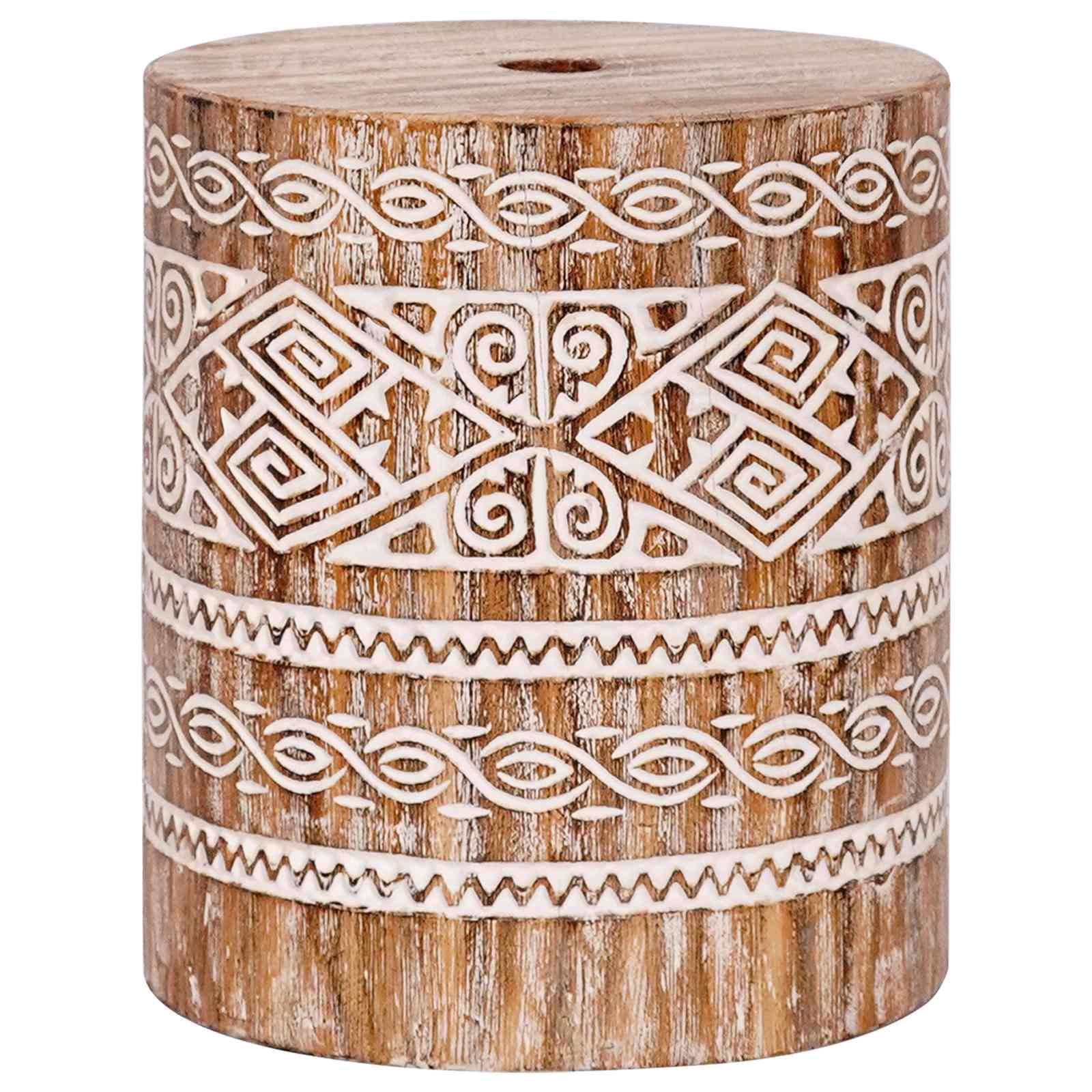 Ein zylindrischer Holzhocker mit aufwendigen geometrischen und Spiralschnitzereien in Weiß, die ein rustikales und künstlerisches Design betonen.