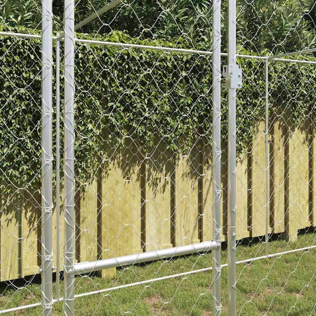 Ein Maschendrahtzaun mit einer grünen Hecke und einem Holz-Sichtschutzzaun dahinter, auf einer Rasenfläche, unter einem sonnigen Himmel.