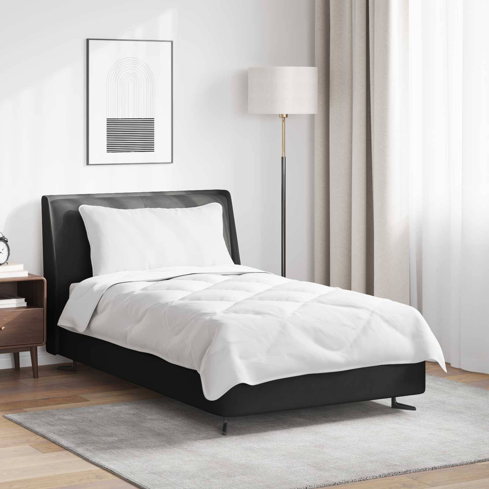 Ein modernes Schlafzimmer zeigt ein ordentlich gemachtes Bett mit weißer Bettwäsche, einer Lampe und einem gerahmten Kunstwerk. Licht filtert durch beige Vorhänge.