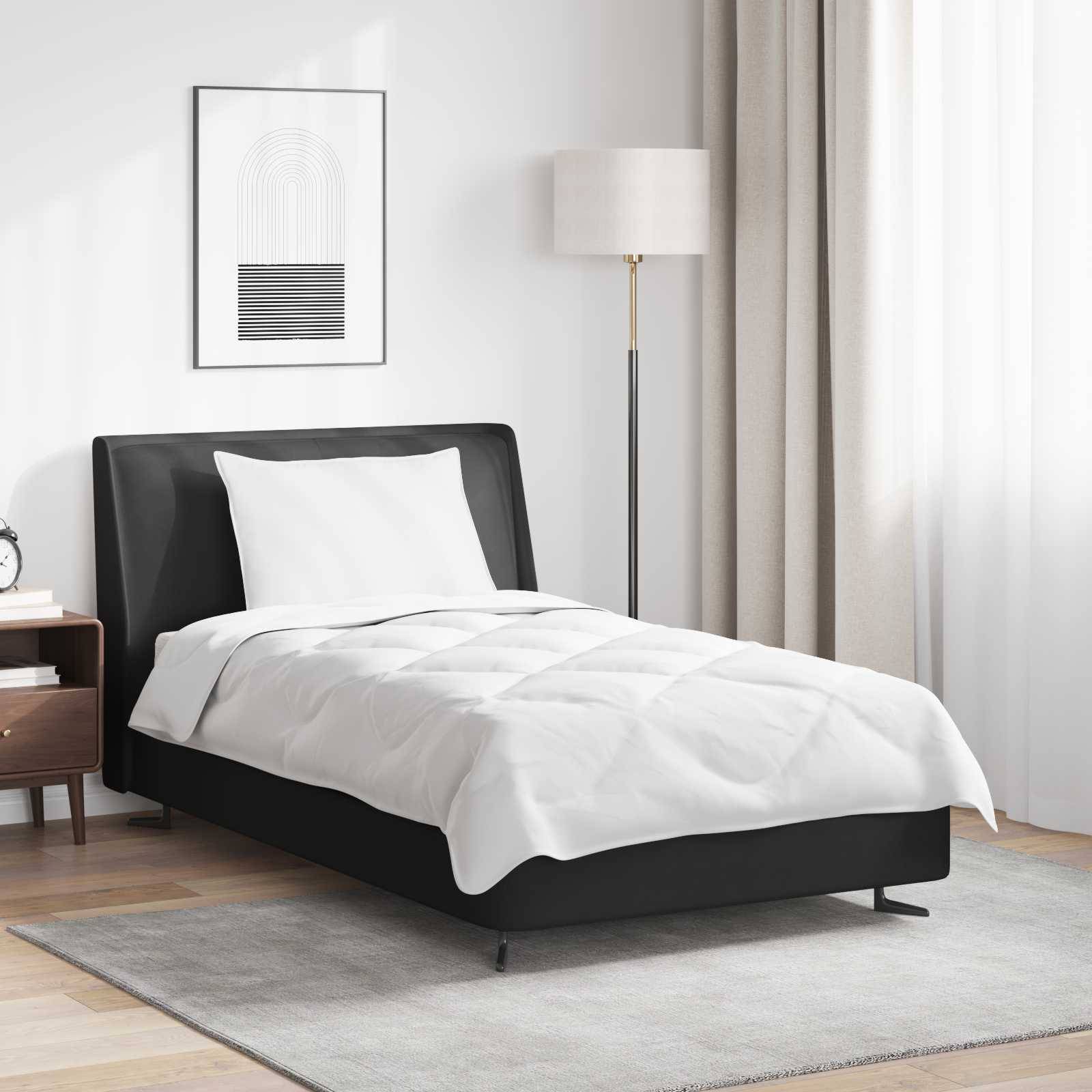 Ein modernes Schlafzimmer zeigt ein sorgfältig gemachtes Bett mit weißer Bettwäsche, einem schwarzen Rahmen, einer Stehlampe, einem Nachttisch mit Dekoration und einem gerahmten Kunstwerk.