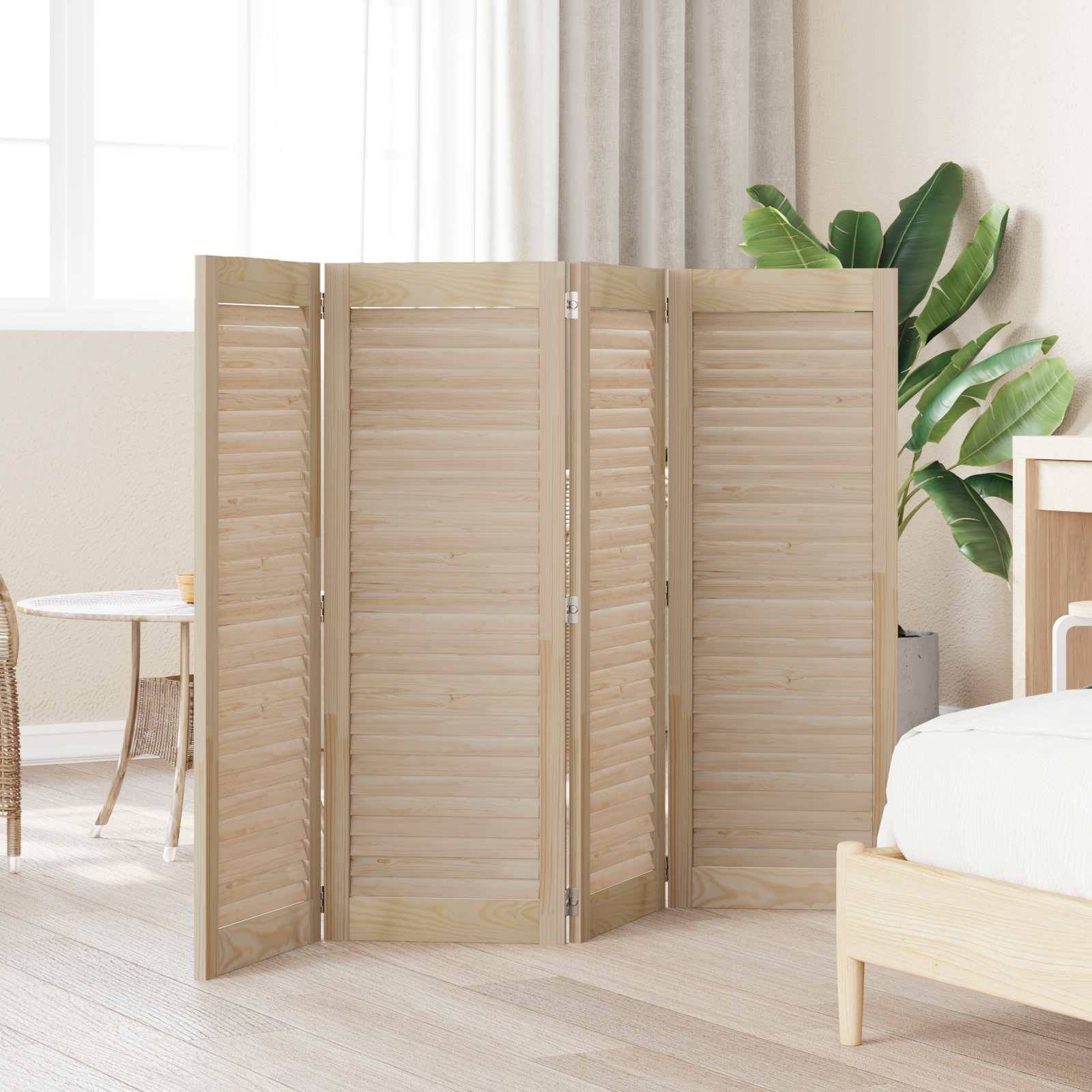 Ein hölzerner Paravent steht in einem hellen Raum mit beigefarbenem Teppich, umgeben von einem Korbstuhl, einer Pflanze und einem Bett.