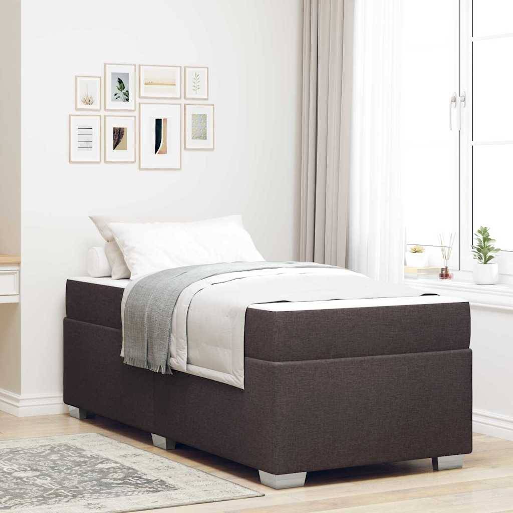 Einzelbett mit dunkel gepolstertem Bettgestell, weißer Bettwäsche und grauer Wurfdecke in einem hellen minimalistischen Schlafzimmer in der Nähe eines Fensters.