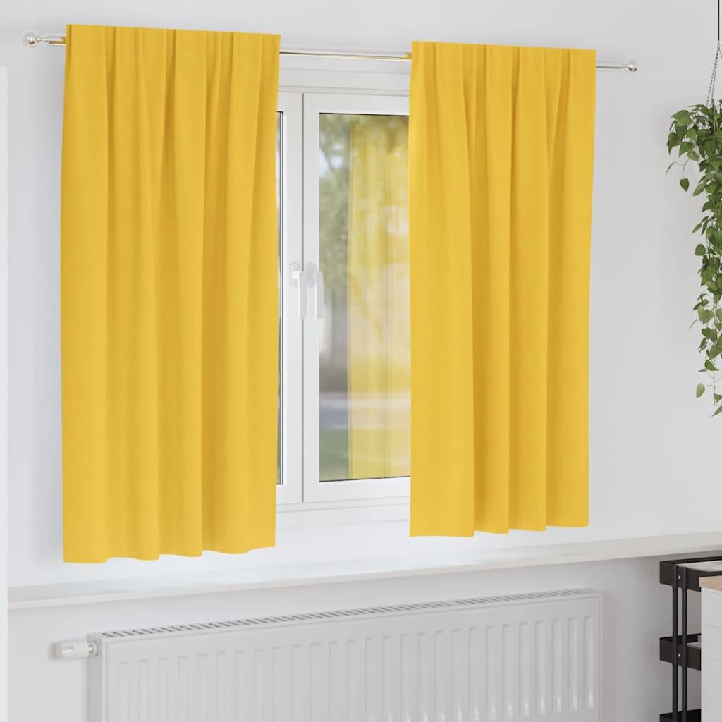 Ein Fenster mit hellen gelben Vorhängen steht offen und gibt einen Busch im Freien preis. Unterhalb des Fensters befindet sich ein weißer Heizkörper an einer weißen Wand.