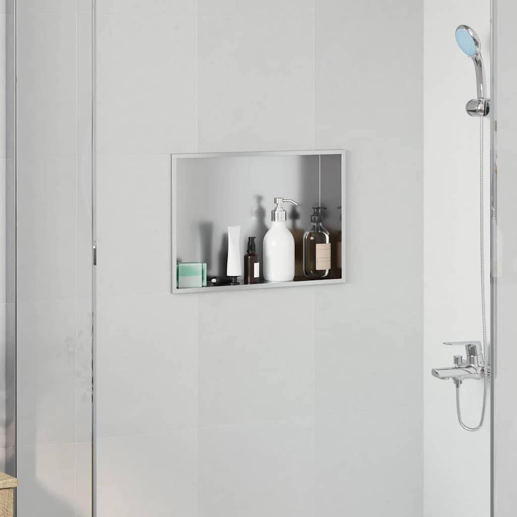 Eine moderne Duschzone mit einem silbernen Duschkopf und einer Nischenablage, die Toilettenartikelflaschen vor hellgrauen Fliesen enthält.