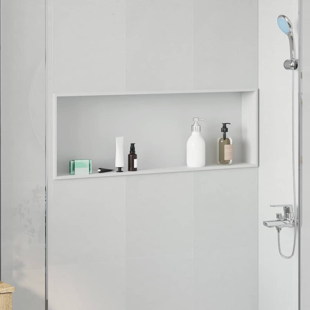 Ein minimalistisches Badezimmer mit einem ordentlich organisierten Duschablage, auf der drei Flaschen stehen - eine in hellem Grün, eine in Weiß und eine in Braun - neben einem Duschkopf.