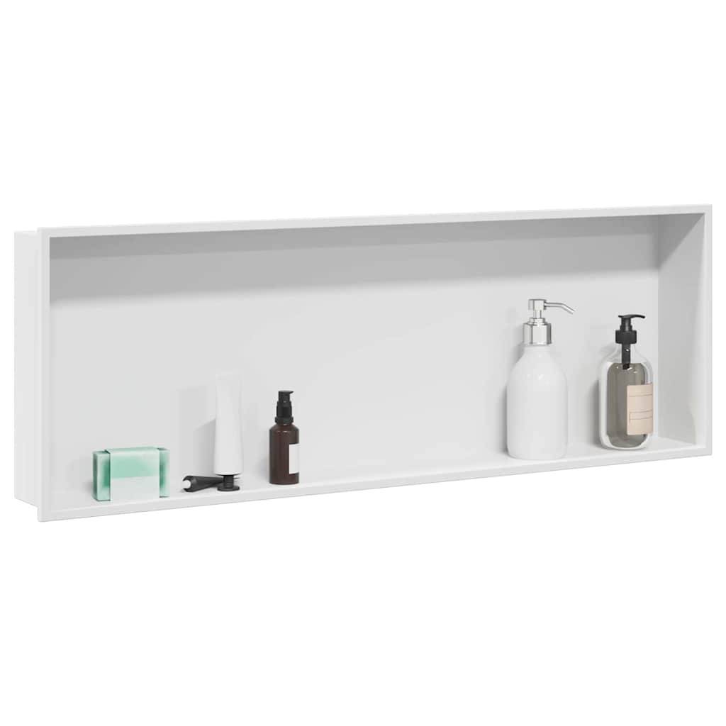 Ein weißes, an der Wand befestigtes Regal mit Badezimmerartikeln: eine durchsichtige Seifenbar, eine schwarze Klammer, eine weiße Tube, eine braune Flasche und zwei Seifenspender.