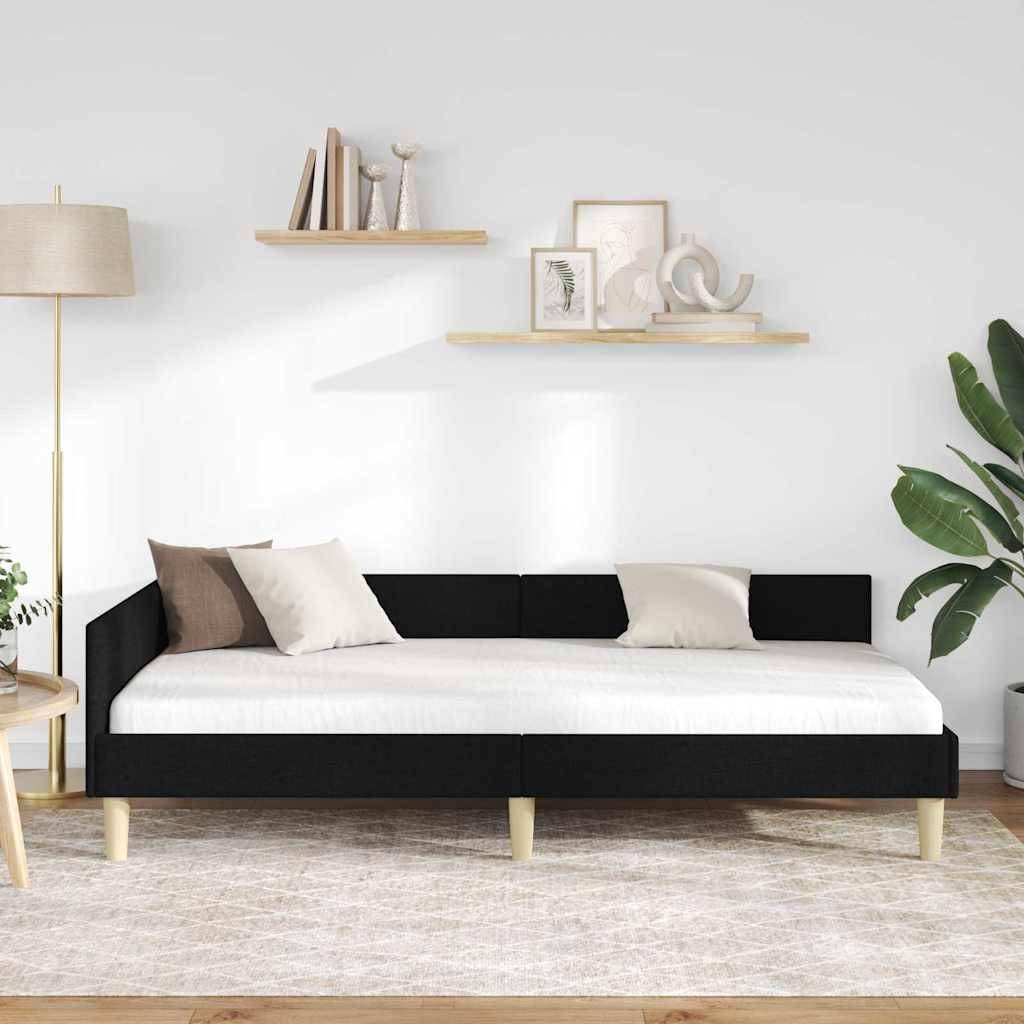 Ein modernes Wohnzimmer mit einem schwarzen Tagesbett mit weißen Kissen, einer Pflanze, einer Stehleuchte und zwei schwebenden Regalen mit Dekorationselementen darüber.