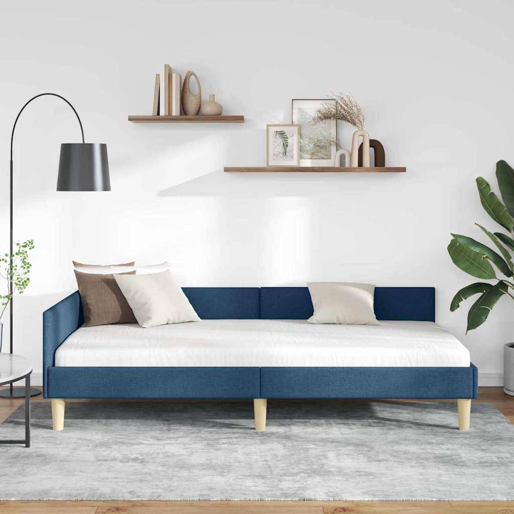 Ein modernes Wohnzimmer mit einem marineblau-farbenen Tagesbett, weißen Kissen, einer schwarzen Stehlampe und Pflanzen. Regale mit Dekorationselementen und sanftem Licht vervollständigen den Raum.