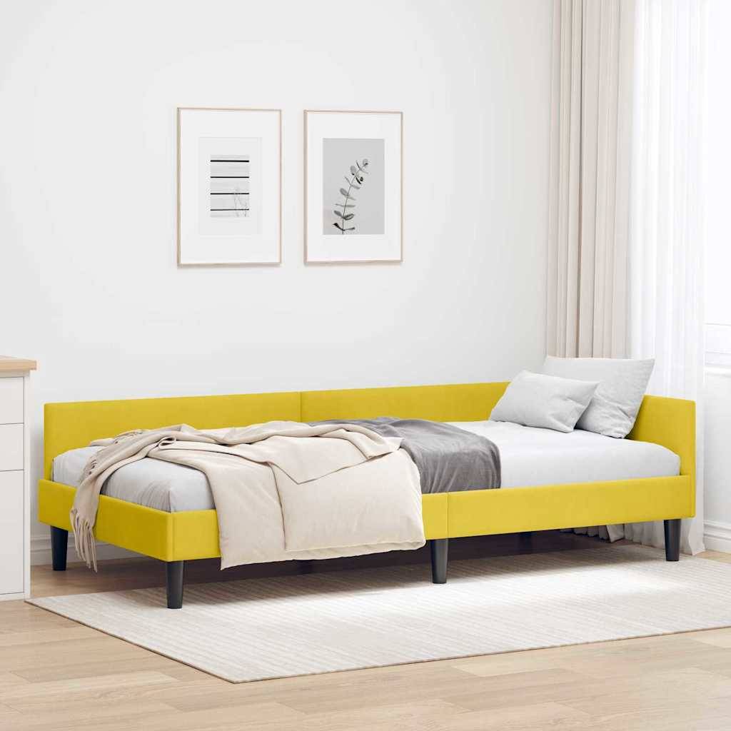 Ein modernes Schlafzimmer mit einem gelb gepolsterten Bett, beigefarbener Decke, grauen Kissen, weißer Kommode und zwei gerahmten Kunstwerken an der Wand.