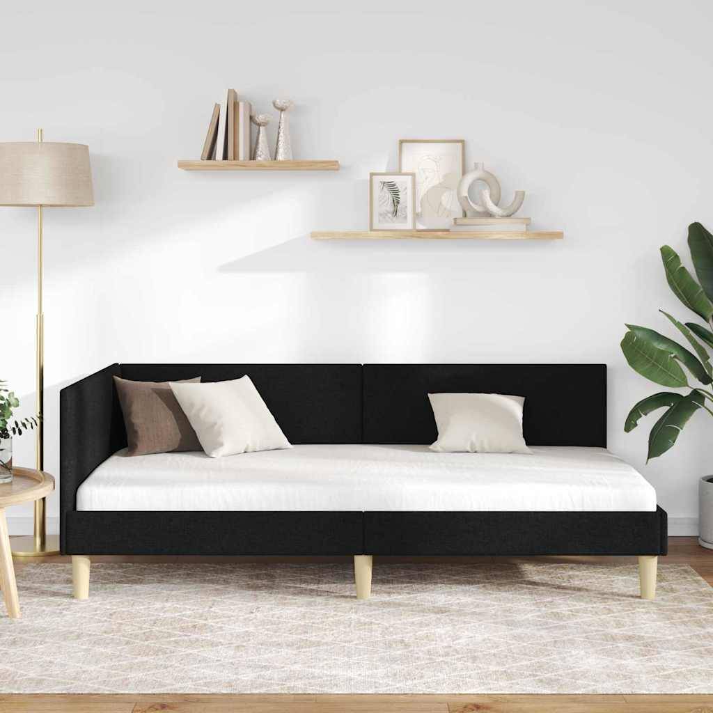 Ein modernes schwarzes Tagesbett mit weißen Kissen befindet sich in einem Wohnzimmer. Es wird flankiert von einem hölzernen Beistelltisch mit einer Lampe und einer großen grünen Pflanze.