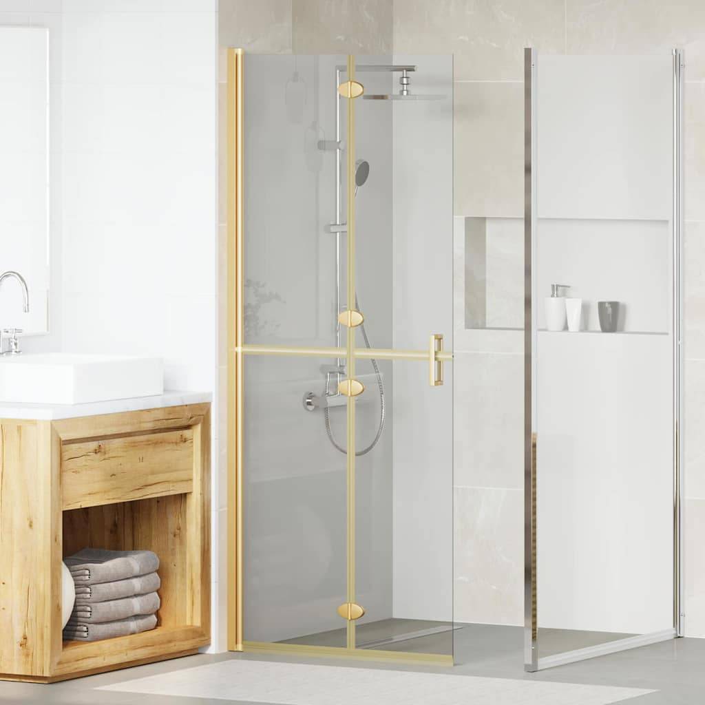 Ein modernes Badezimmer verfügt über eine Glasduschkabine mit goldenen Verzierungen, einen Waschtisch aus Holz mit einem Waschbecken und zusammengelegte Handtücher auf einem Regal.