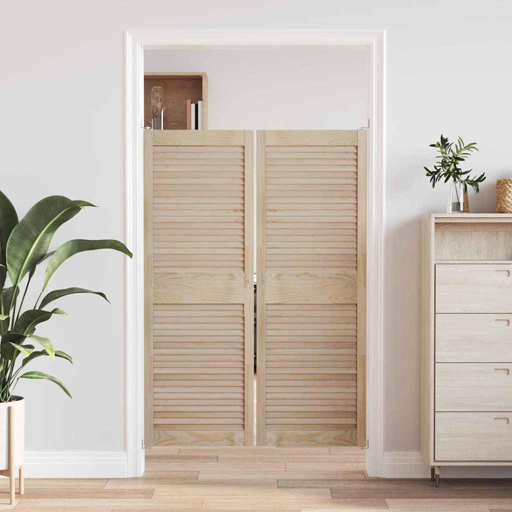 Eine Holz-Lamellentür im Saloon-Stil ist in einem Innentürrahmen installiert, flankiert von einer Pflanze und einer minimalistischen Kommode auf einem Holzboden.