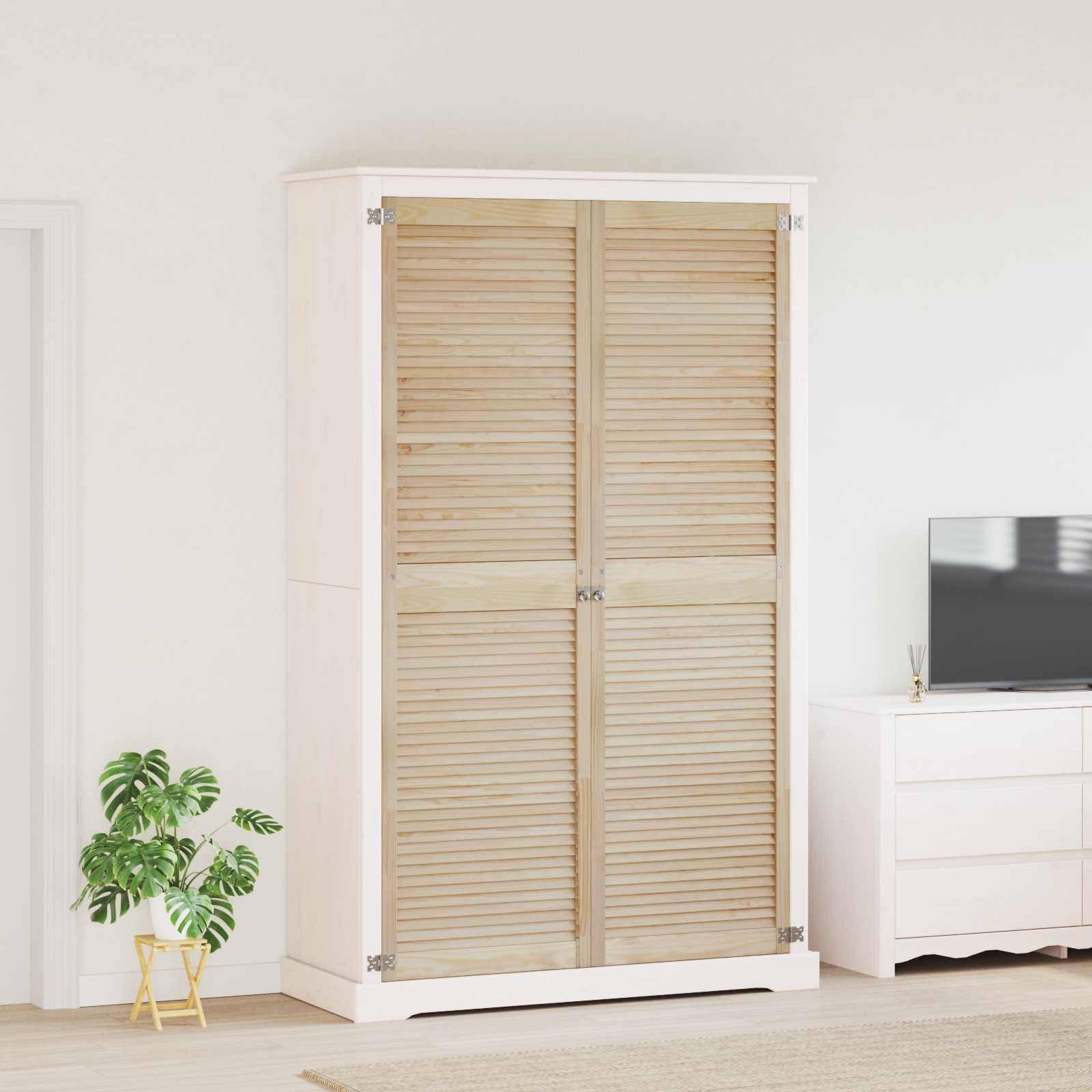 Ein weißer Kleiderschrank mit Holzlamellentüren steht zwischen einer kleinen Pflanze auf der linken Seite und einer weißen Kommode mit einem Fernseher auf der rechten Seite.