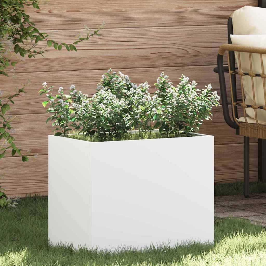 Eine rechteckige weiße Pflanzbox, gefüllt mit üppig grünen Pflanzen, die im Freien auf Gras platziert ist, mit Holzvertäfelung und einem Korbstuhl in der Nähe.