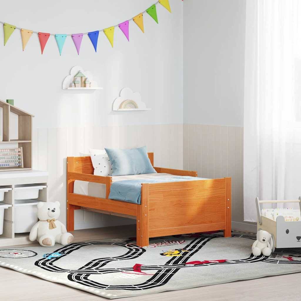 Ein Kinderzimmer mit einem Holzbett, blauen Kissen, bunter Wimpelkette an der Wand, Eisenbahnteppich und Plüschtieren. Hell und verspielt.