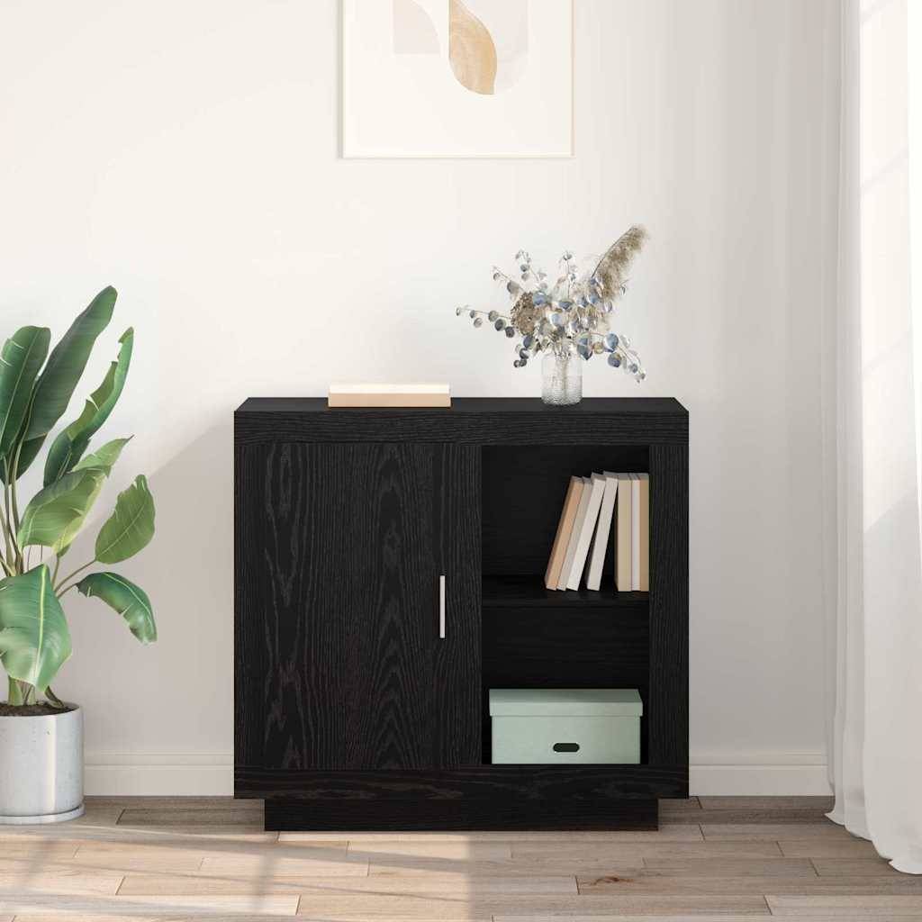 Ein kleiner schwarzer Holzschrank mit Büchern und einer Aufbewahrungsbox, begleitet von einer Pflanze und einer Vase mit getrockneten Blumen, vor einer hellen Wand.