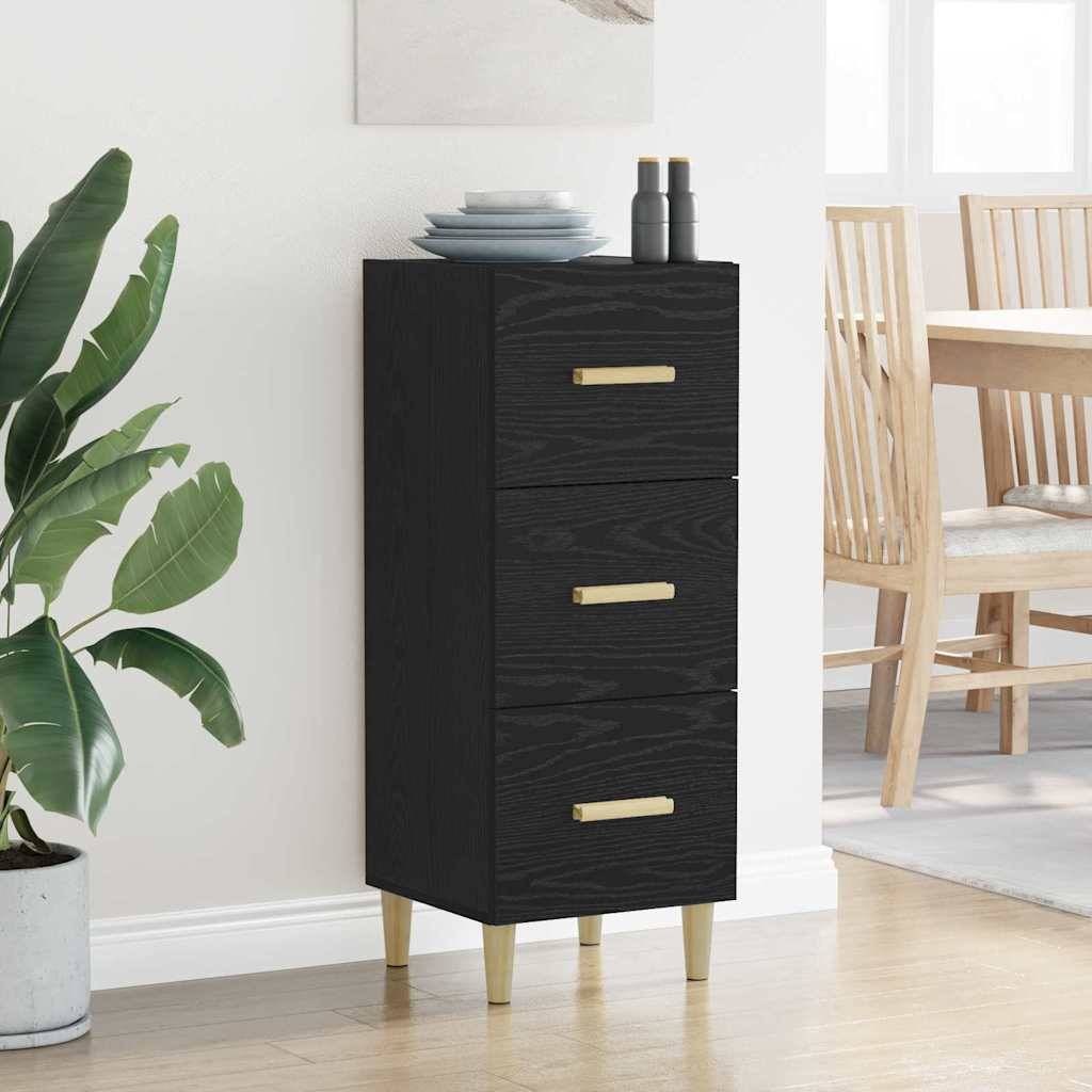 Ein schwarzer Schubladenschrank mit goldenen Griffen steht in einem hellen Raum. Eine Topfpflanze befindet sich links, und ein Holzstuhl steht im Hintergrund.