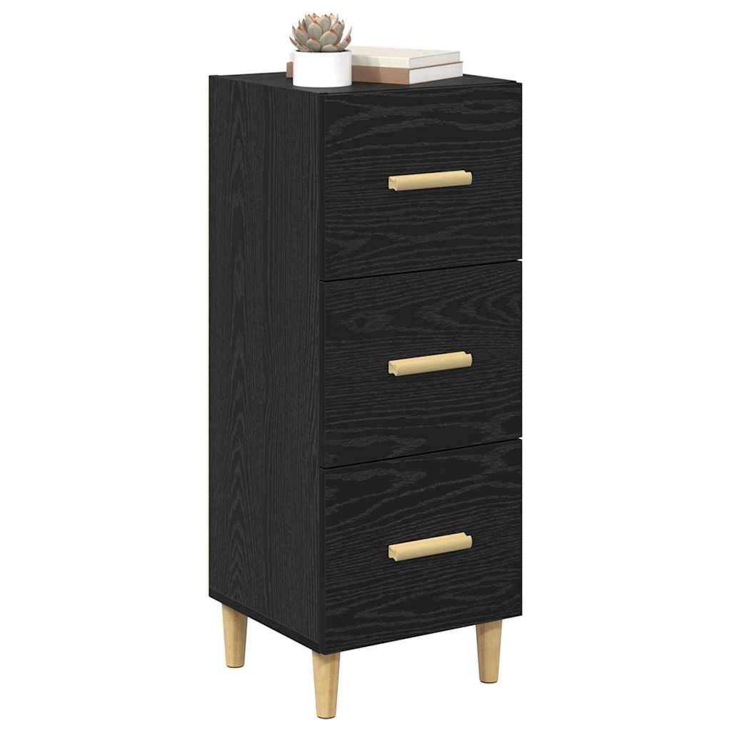Ein hoher, schwarzer Holzschrank mit drei Schubladen, goldenen Griffen und hellen Holzbeinen. Eine kleine Topfpflanze und zwei Bücher ruhen auf der Oberfläche.