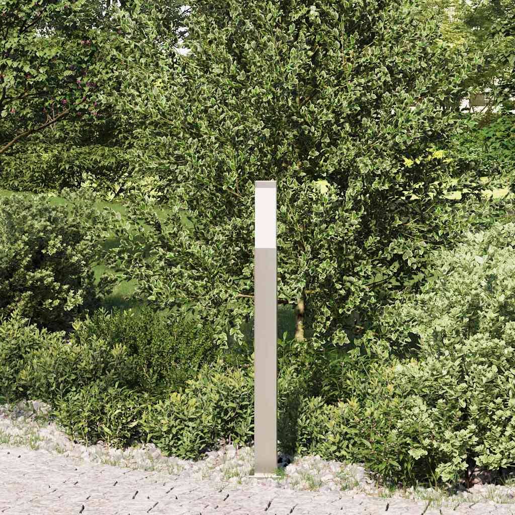 Eine moderne, rechteckige Außenlampe steht inmitten üppiger Vegetation und Bäumen und fügt sich harmonisch in die natürliche Landschaft entlang eines Steinweges ein.