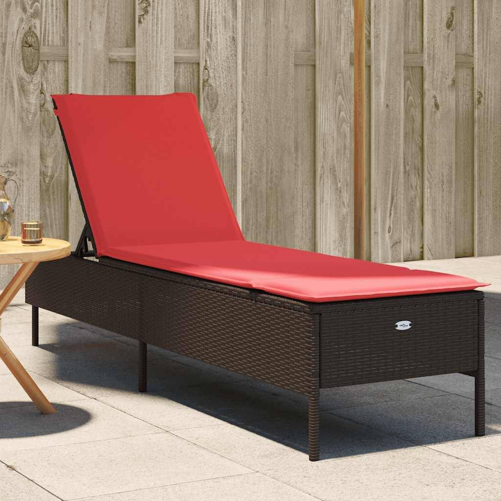 Ein roter gepolsterter Liegestuhl im Freien auf einer Terrasse, neben einem kleinen Holztisch mit Kerzen, vor einem Holzzaun im Hintergrund.