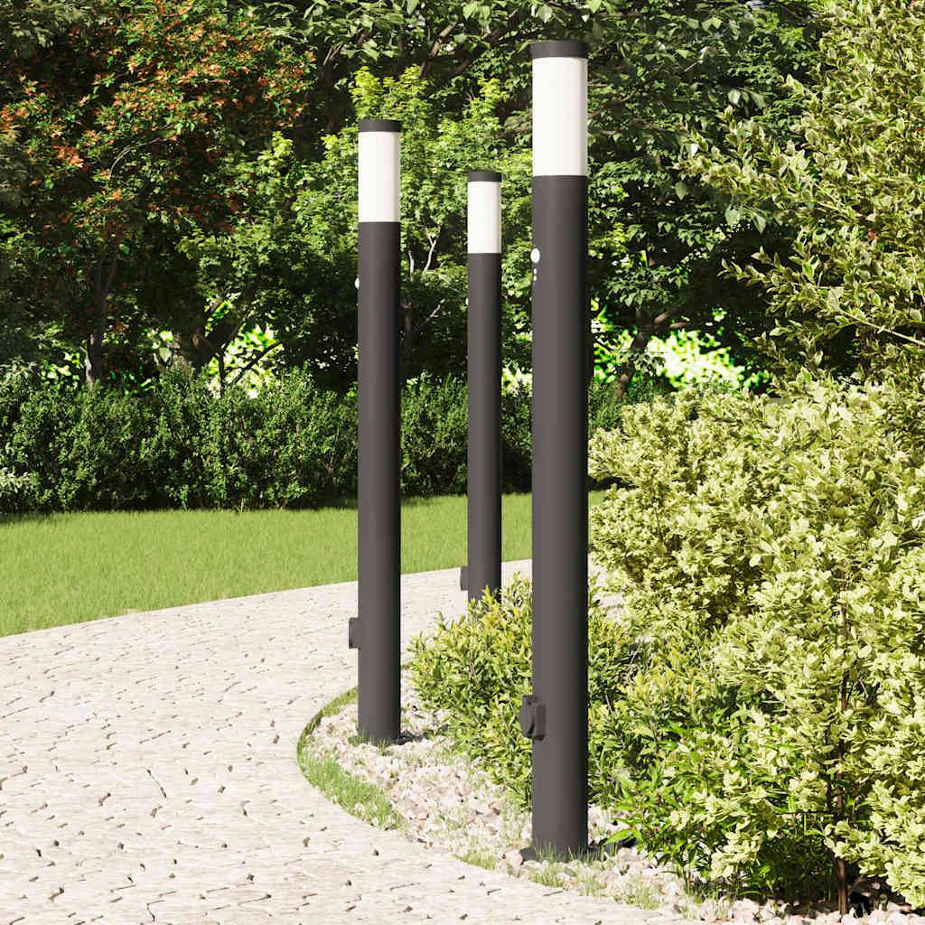Eine Reihe moderner schwarz-weißer Straßenlampen säumt einen geschwungenen Steinweg, der von üppigem grünem Laub und Bäumen umgeben ist.
