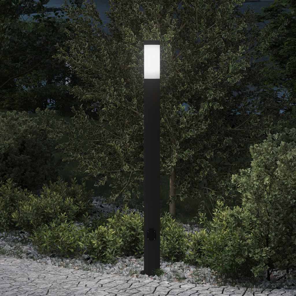 Eine beleuchtete Straßenlaterne steht auf einem Kopfsteinpflasterweg, umgeben von Büschen und Bäumen in der Nacht und schafft eine ruhige und friedliche Atmosphäre.