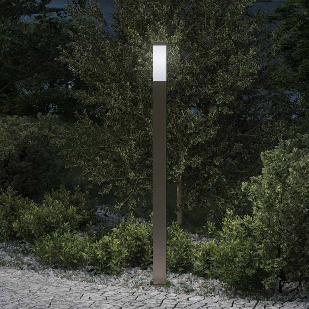 Eine moderne, hohe Gartenlaterne erhellt hell einen Gartenweg, der von dichtem Grün und Bäumen während der Nacht umgeben ist.