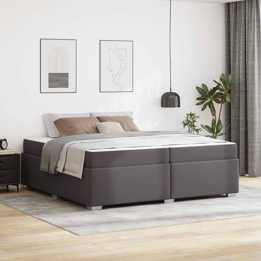 Modernes Schlafzimmer mit grauem gepolstertem Stauraumbett, Nachttisch, Wandkunst, Pendelleuchte, Pflanzen und Vorhängen in einem hellen, minimalistischen Raum.