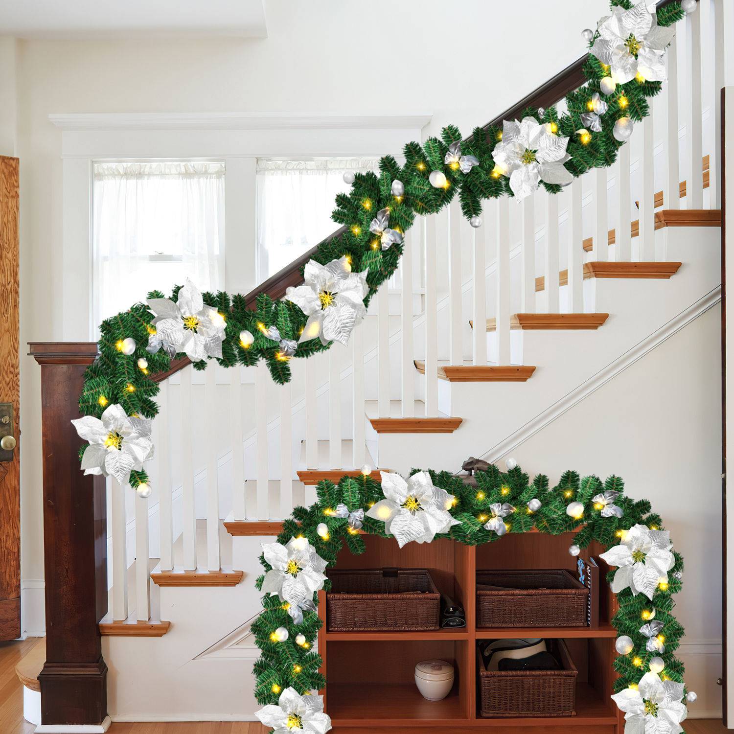 Eine Treppe und ein Regalsystem, dekoriert mit grüner Girlande, weißen Weihnachtssternen und warmen Lichtern in einem hellen Wohnungsinterieur.