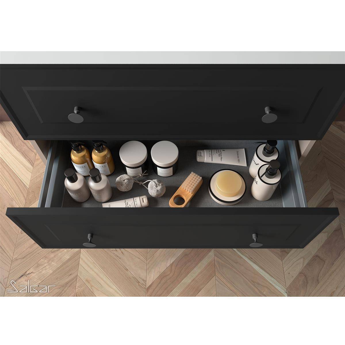 Offene schwarze Badezimmerschublade gefüllt mit Toilettenartikeln, einschließlich Flaschen, Gläser, Tuben, Seife und einem Holzpinsel-Organizer.