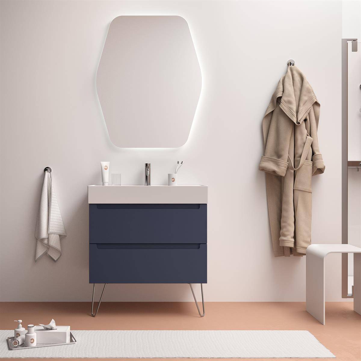 Modernes Badezimmer mit marineblauem Waschtisch und Spiegel, ein Bademantel an der Wand hängend, ein Handtuchhalter und ein weißer Hocker auf einem pfirsichfarbenen Boden.