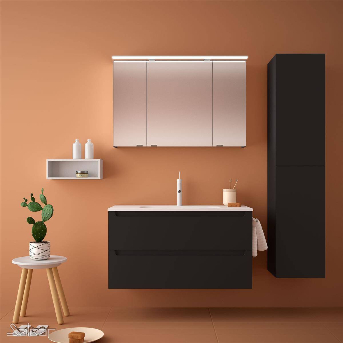 Modernes Badezimmer mit schwarzem Waschtisch, Spiegelschrank, hohlem Aufbewahrungsschrank, Waschbecken und kleinem Hocker mit Pflanze vor einer warmgelben Wand.