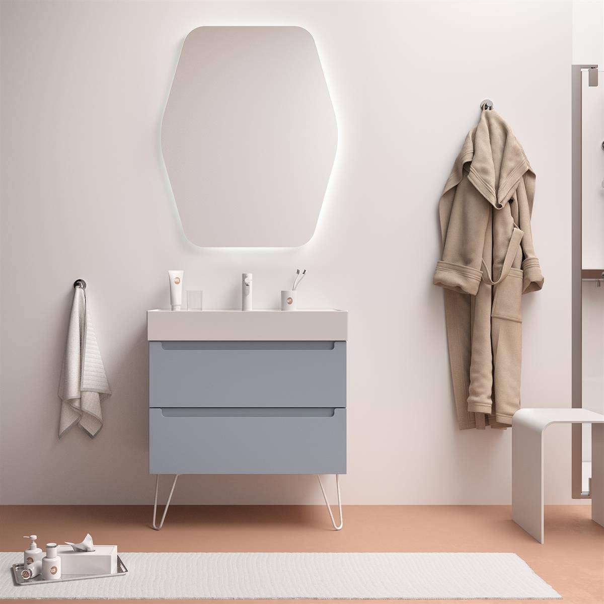 Minimalistischer Badezimmerwaschtisch mit geometrischem Spiegel, hängendem Bademantel und Handtuch sowie einer kleinen Badmatte und Toilettenartikeln auf dem Boden.