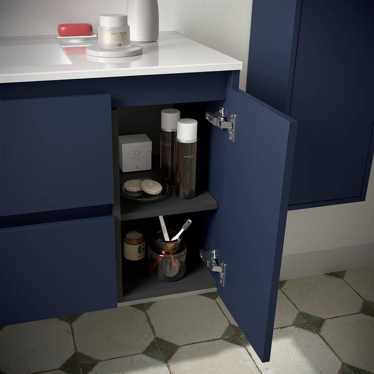 Offener dunkelblauer Badezimmerschrank mit Toilettenartikeln und Gläsern innen, unter einer weißen Arbeitsplatte auf gemustertem Fliesenboden.