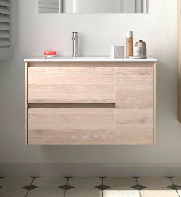 Schwebendes Badezimmermöbel aus hellem Holz mit weißem Waschbecken und verchromtem Wasserhahn, bestückt mit Toilettenartikeln und einem Spiegel darüber auf gefliesten Bodenflächen.