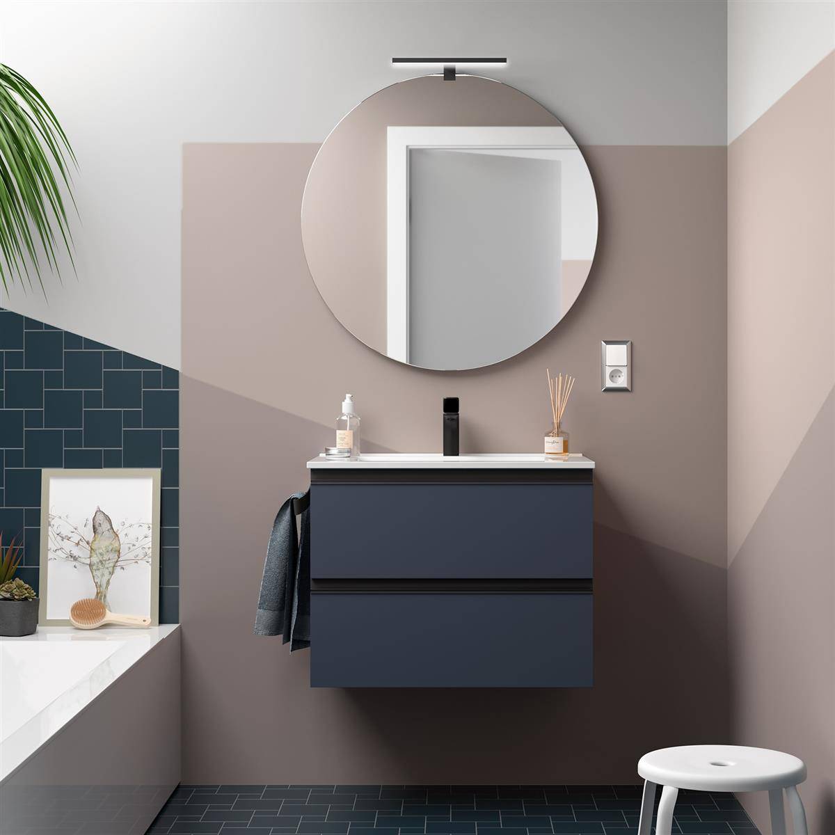 Modernes Badezimmer mit einem runden Spiegel über einem dunklen, wandmontierten Waschtisch, angrenzender Badewannennische und weißem Hocker auf Fliesenboden.