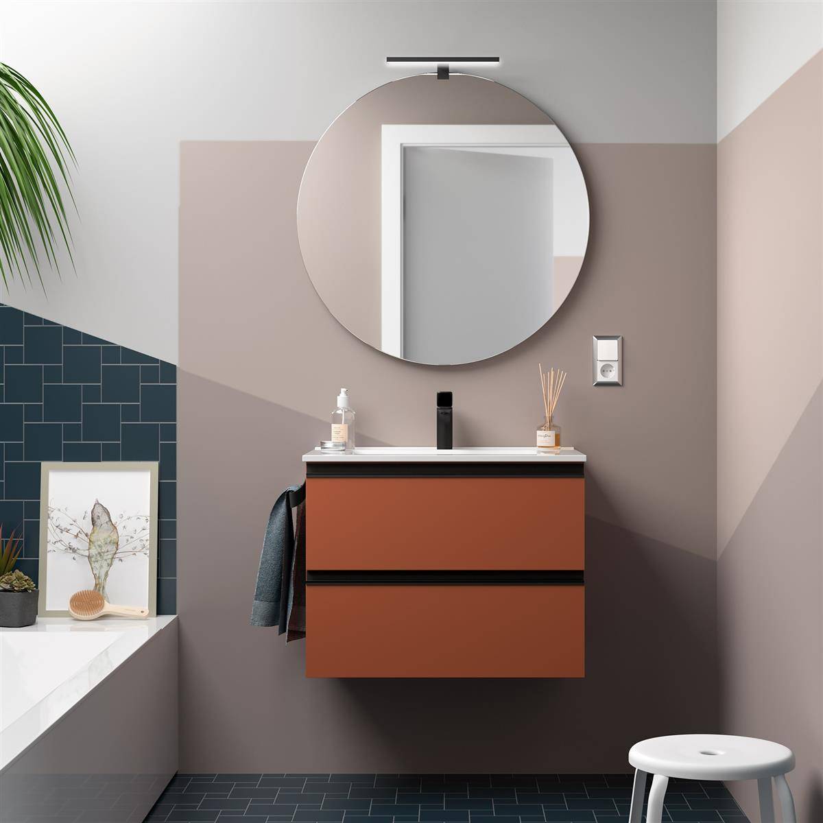 Modernes Badezimmer-Waschtisch mit rundem Spiegel, rostfarbenem schwebendem Schrank, Wandlichtschalter und weißem Hocker neben dem gefliesten Badewannenbereich.