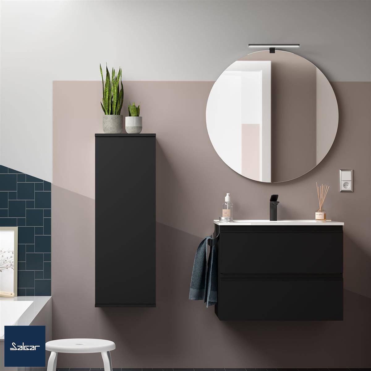 Modernes Badezimmer-Waschbecken mit schwarzen Wandschränken, rundem Spiegel, Waschbecken, Handtuch, Pflanzen und blauer Fliesenwandzierleiste.