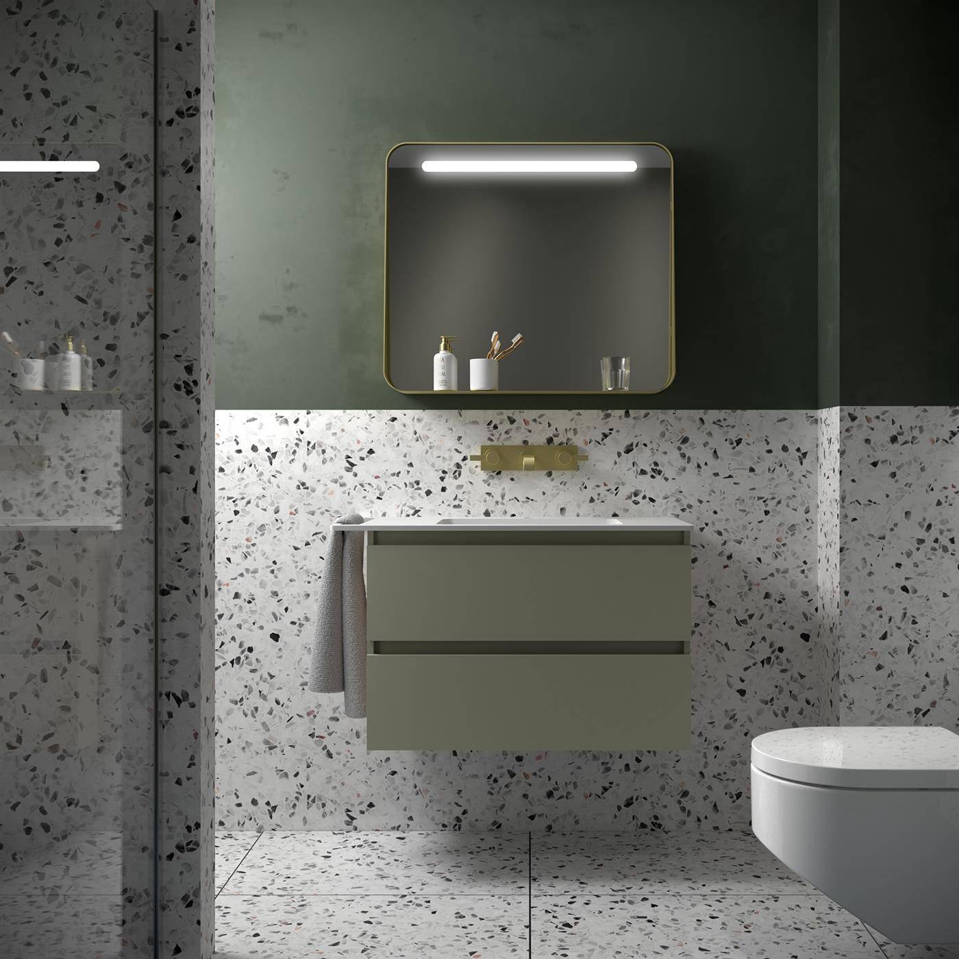 Modernes Badezimmer mit schwebendem Doppelschubladenschrank, beleuchtetem Spiegelschrank, Messingarmaturen, Terrazzogestaltung an Wänden und Boden sowie teilweise sichtbarem Toilettensitz.
