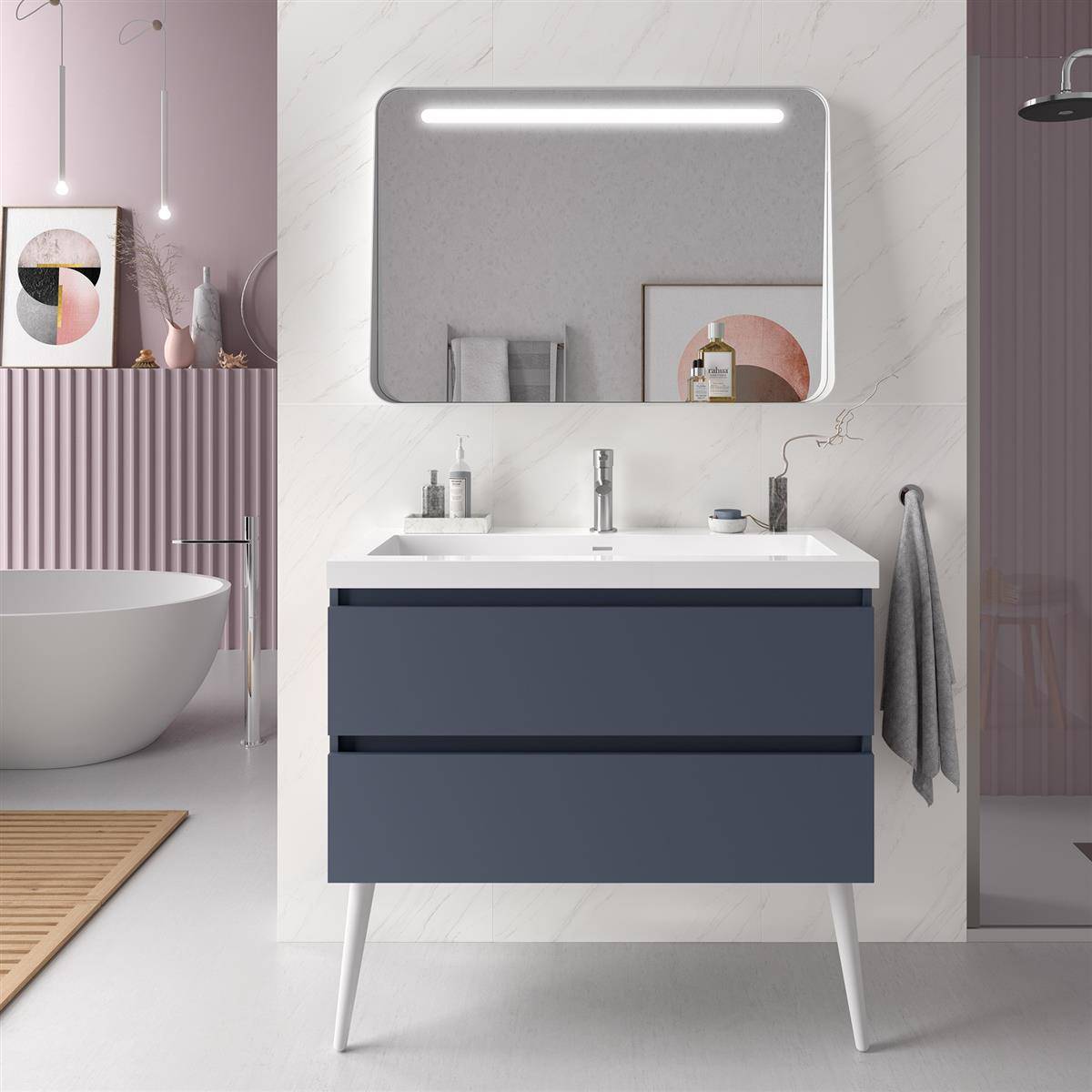 Modernes Badezimmer-Waschtisch mit blauen Schubladen, Waschbecken und beleuchtetem Spiegel vor Marmorwand, neben freistehender Badewanne und Duschbereich gezeigt.