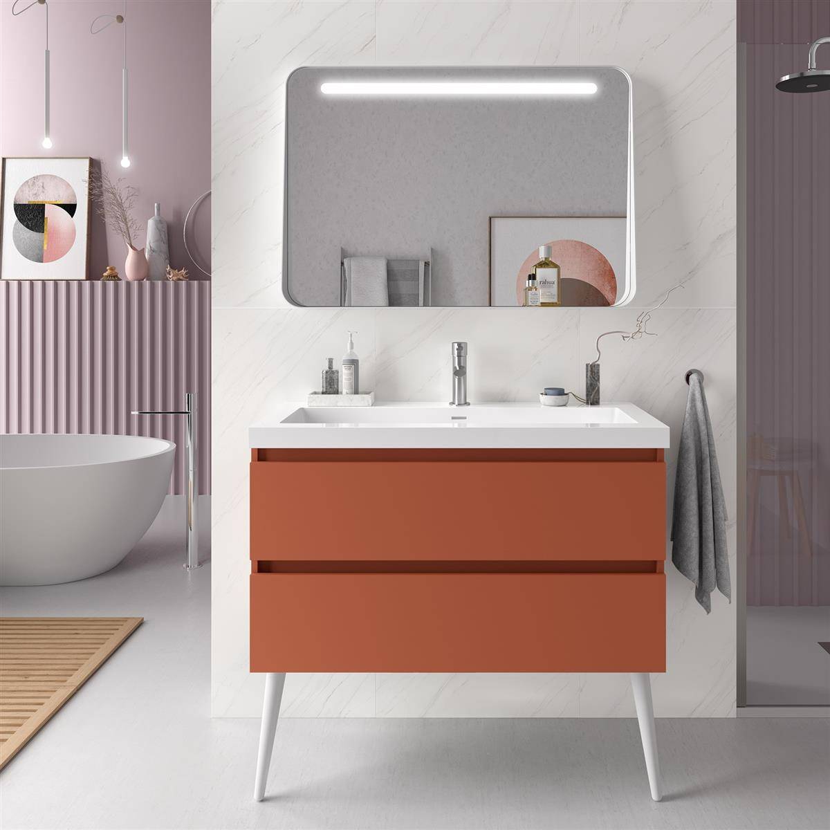 Modernes Badezimmerwaschtisch mit orangefarbenen Schubladen, weißem Waschbecken, beleuchtetem Spiegel und Handtuch; angrenzender Raum zeigt Badewanne und Pastelldekor.