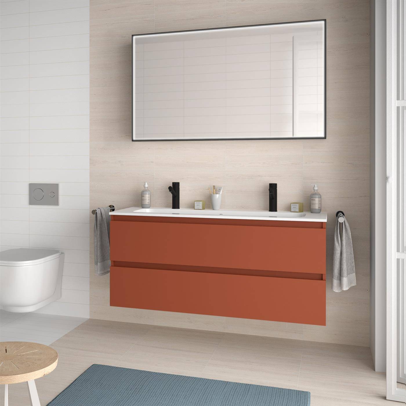 Modernes Badezimmer mit wandmontiertem orangefarbenem Waschtisch, rechteckigem Spiegel, Toilette, Handtuchstangen und einem blauen Teppich auf einem hell gefliesten Boden.