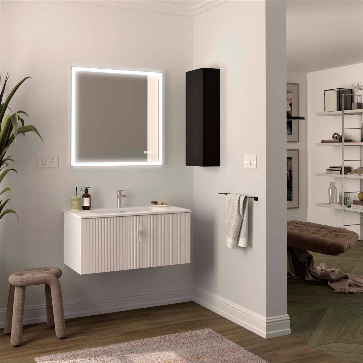 Modernes Badezimmer mit an der Wand montiertem Waschtisch und beleuchtetem Spiegel, schwarzem Schrank, Handtuchstange und Hocker auf Holzboden; angrenzender offener Raum durch die Tür sichtbar.