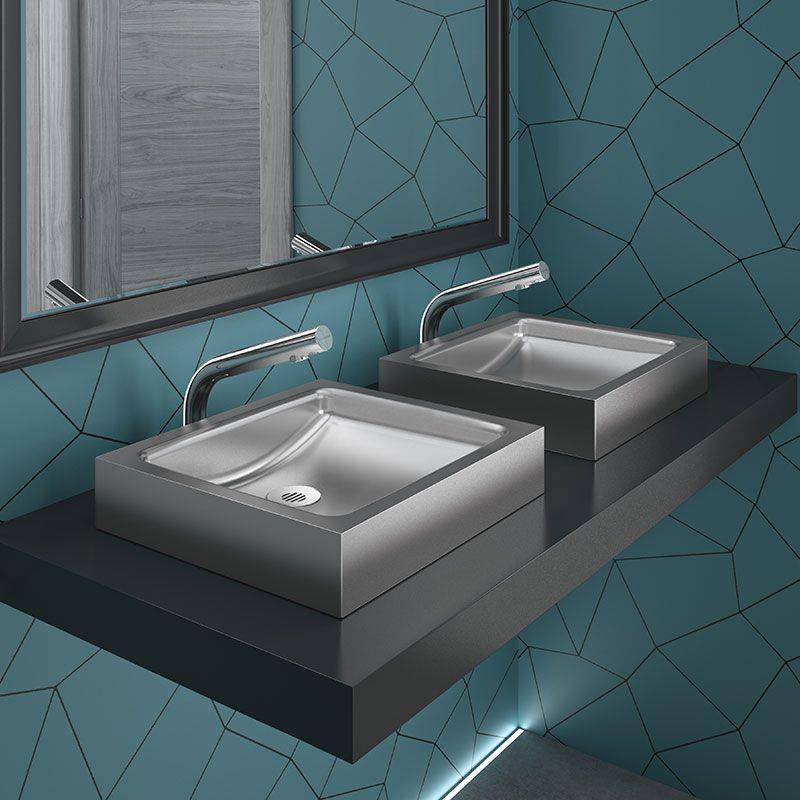 Modernes Badezimmer mit zwei quadratischen Edelstahl-Aufsatzwaschbecken auf einer schwebenden dunklen Arbeitsplatte unter einem Spiegel vor blauem geometrisch gefliestem Wandbelag.