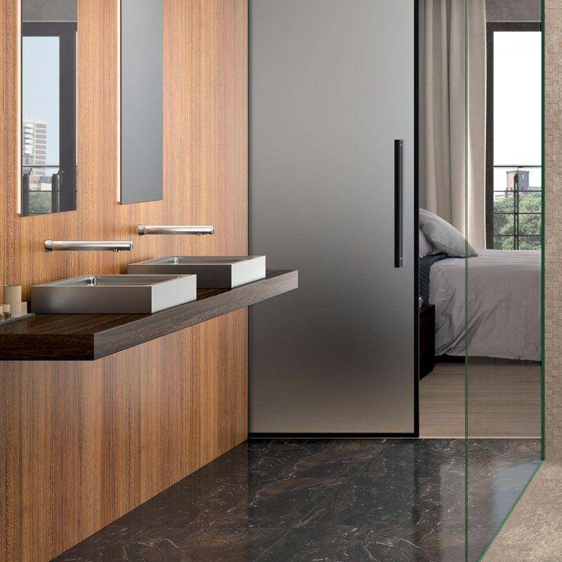 Modernes Badezimmertablett mit Doppelwaschbecken und Spiegel neben einer Glaskugel, mit einem Schlafzimmer, das durch die Tür dahinter sichtbar ist.